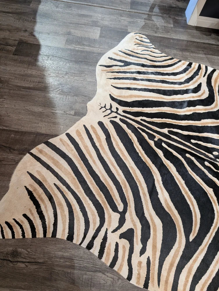 A large cowhide plush zebra print rug with bold black and tan stripes on cream base by angus oliver