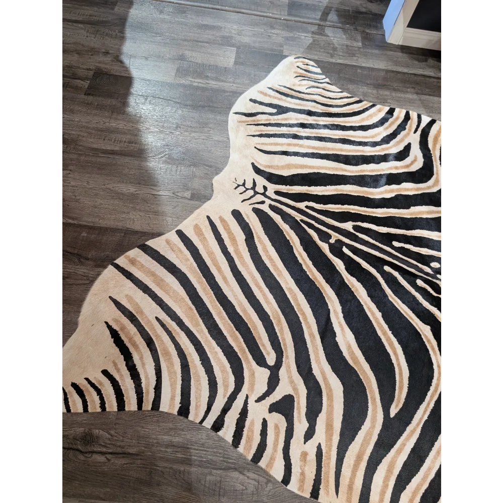 A large cowhide plush zebra print rug with bold black and tan stripes on cream base by angus oliver