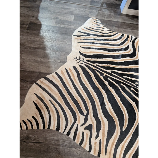 A large cowhide plush zebra print rug with bold black and tan stripes on cream base by angus oliver