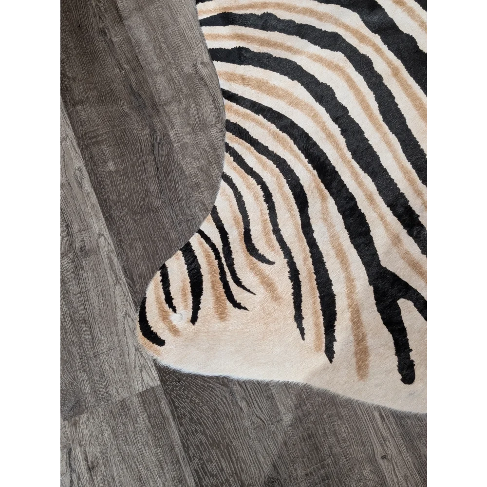 A large cowhide zebra print rug in cream with bold black and tan stripes showing unique characteristics by angus oliver