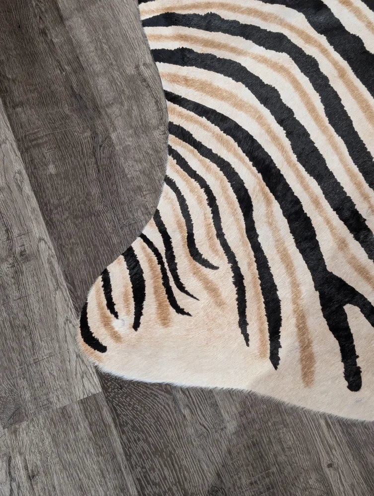 A large cowhide zebra print rug in cream with bold black and tan stripes showing unique characteristics by angus oliver