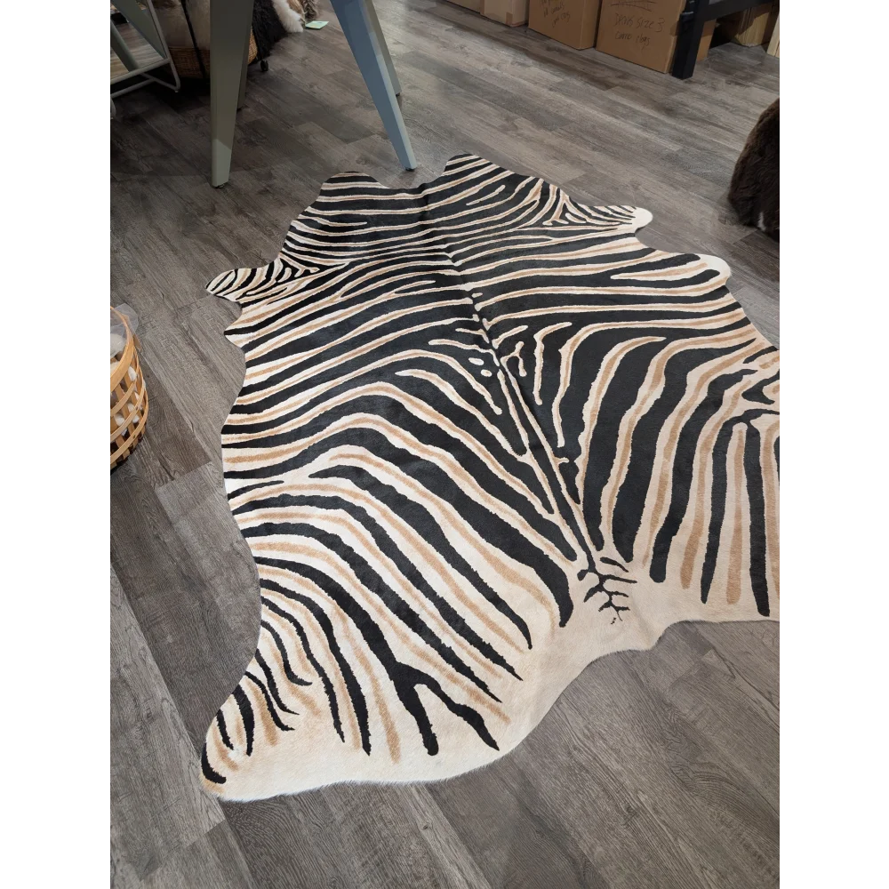 A large black and beige zebra printed cowhide rug with unique characteristics and a natural textured surface by angus oliver