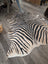 A large black and beige zebra printed cowhide rug with unique characteristics and a natural textured surface by angus oliver