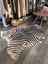 Large cowhide zebra print rug with bold black and beige stripes showcasing unique characteristics by angus oliver