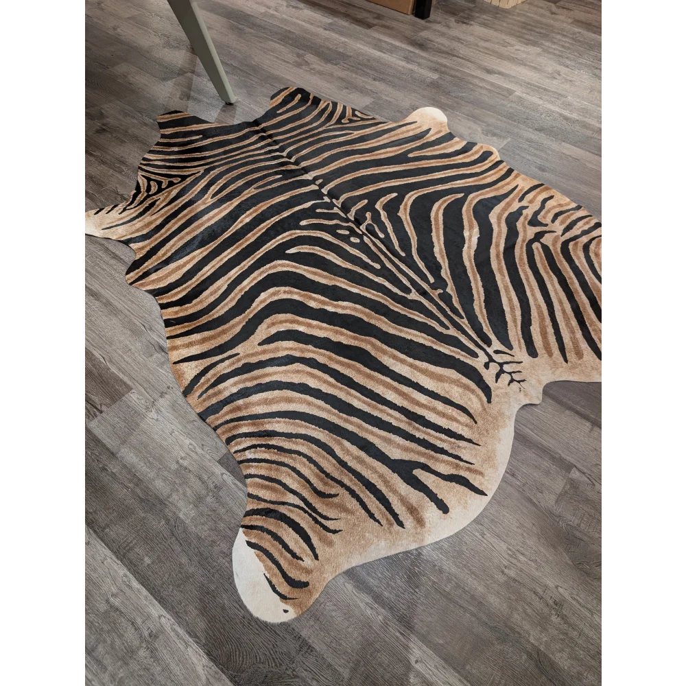 A large cowhide zebra print rug by angus oliver with bold black and tan stripes and unique characteristics