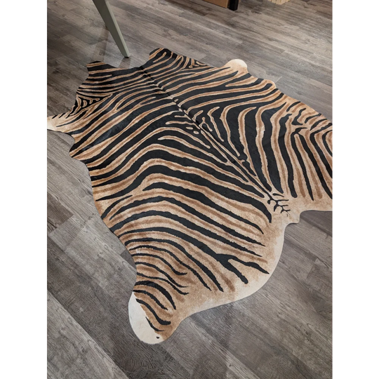 A large cowhide zebra print rug by angus oliver with bold black and tan stripes and unique characteristics