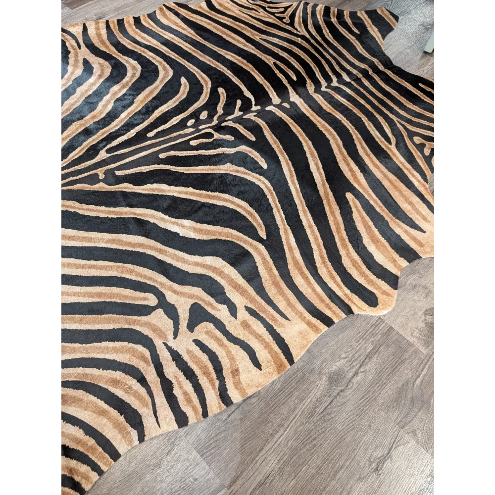A large cowhide rug from angus oliver with bold black and tan zebra print and soft textured surface showing unique characteristics