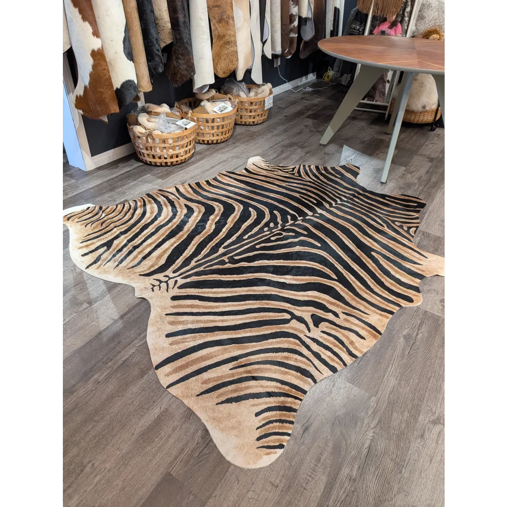 Large cowhide zebra printed rug with bold black and tan stripes on wooden floor by angus oliver