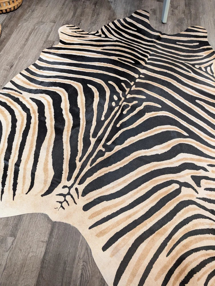 A large cowhide zebra printed rug with bold black and beige stripes and unique characteristics by angus oliver