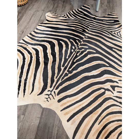 A large cowhide zebra printed rug with bold black and beige stripes and unique characteristics by angus oliver